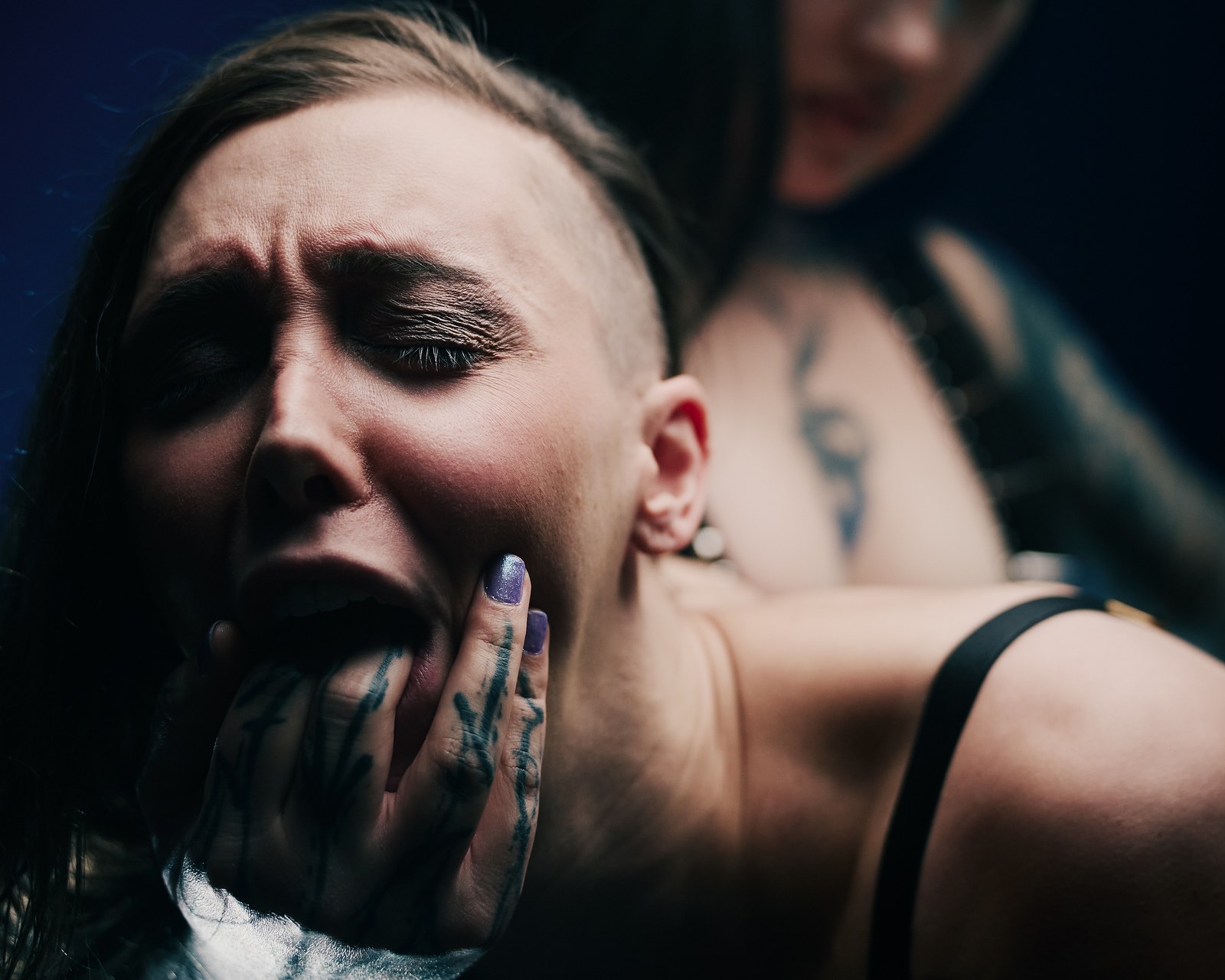 Miss Evilia ja Jade intensiivisessä alistumisen BDSM-lähikuvassa, jossa tatuoitu käsi ohjaa Jaden kasvoja.