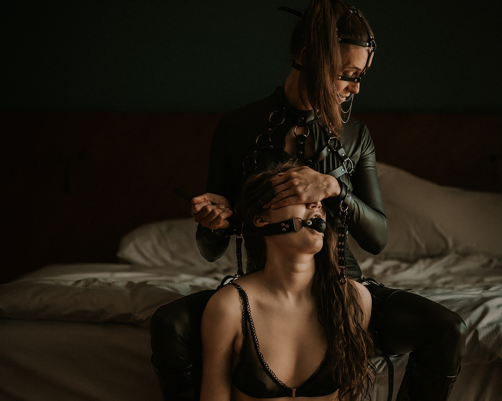 Jade ohjaa suukapulassa olevaa alistujaa hotellihuoneen BDSM-dominointikuvassa.